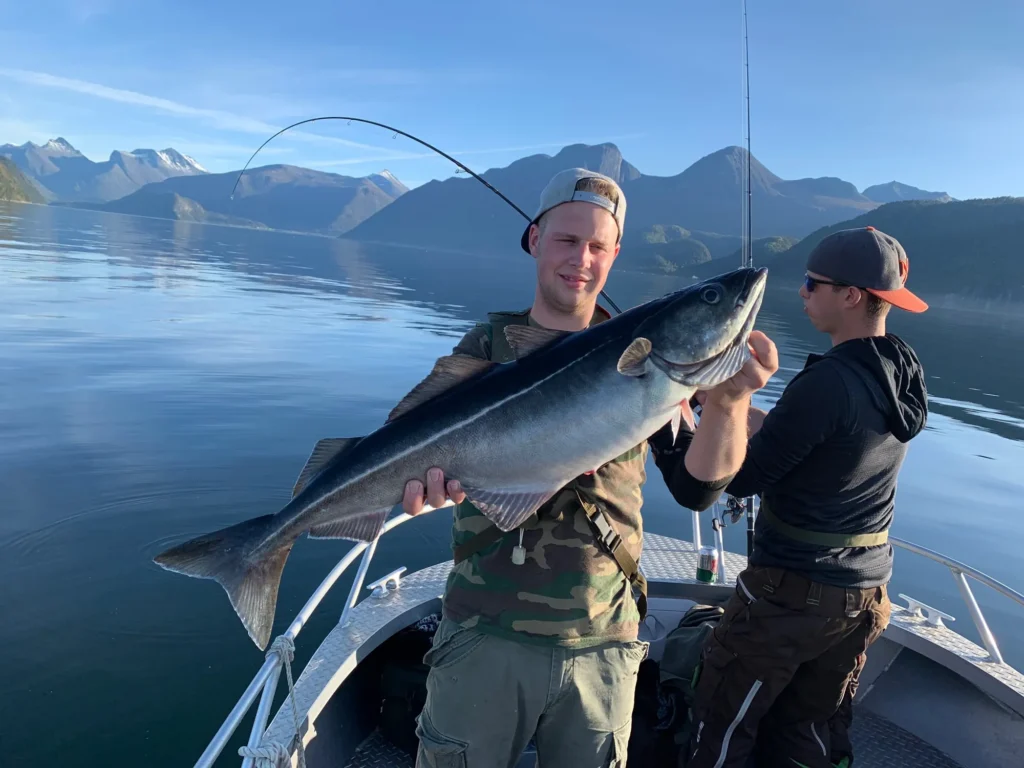 Angelgast mit Fisch und Rettungsweste im Boot auf dem Fjord