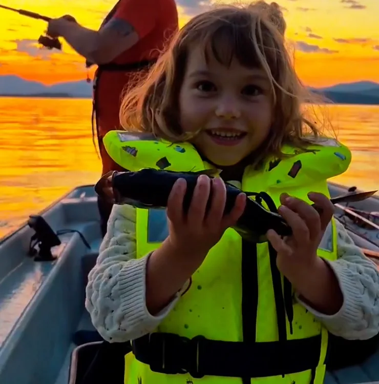 Kind mit Rettungsweste hält einen gefangenen Fisch