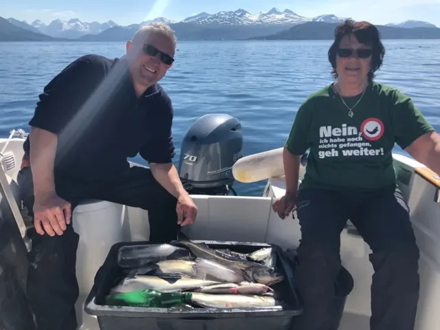 Zwei Angelgäste im Boot vor schneebedeckten Bergen